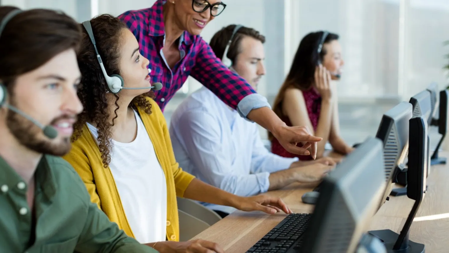 Leidinggevende geeft instructies aan medewerkers van callcenter.