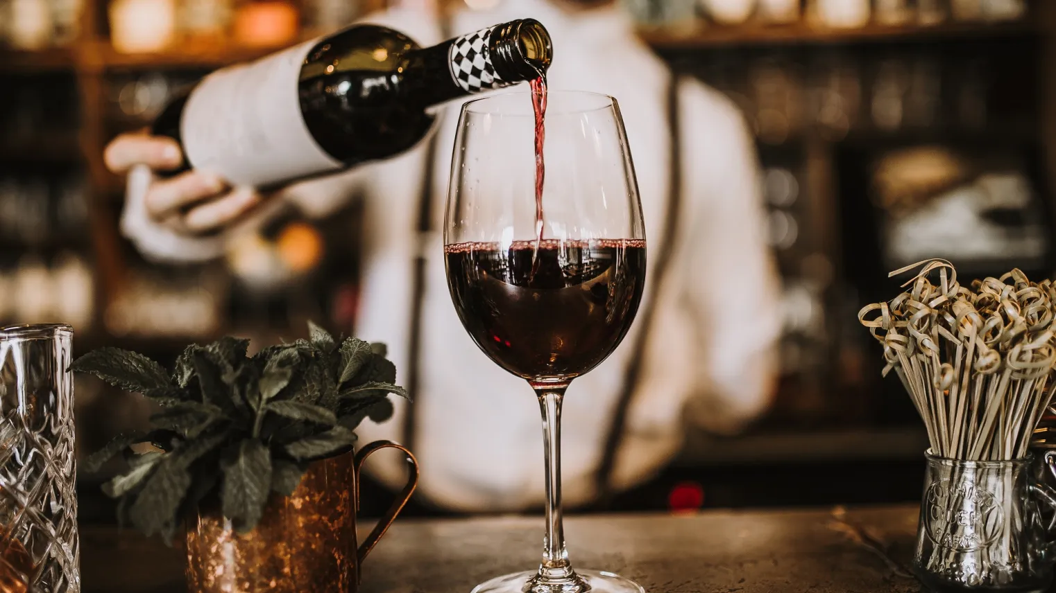 Een ober schenkt wijn in een glas in een restaurant.