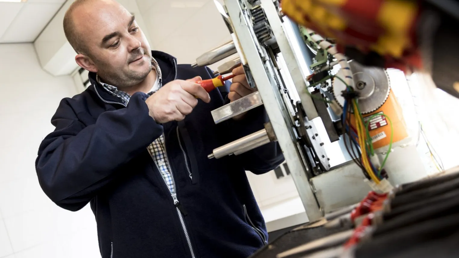 Student aan het werk bij een machine met een schroevendraaier 