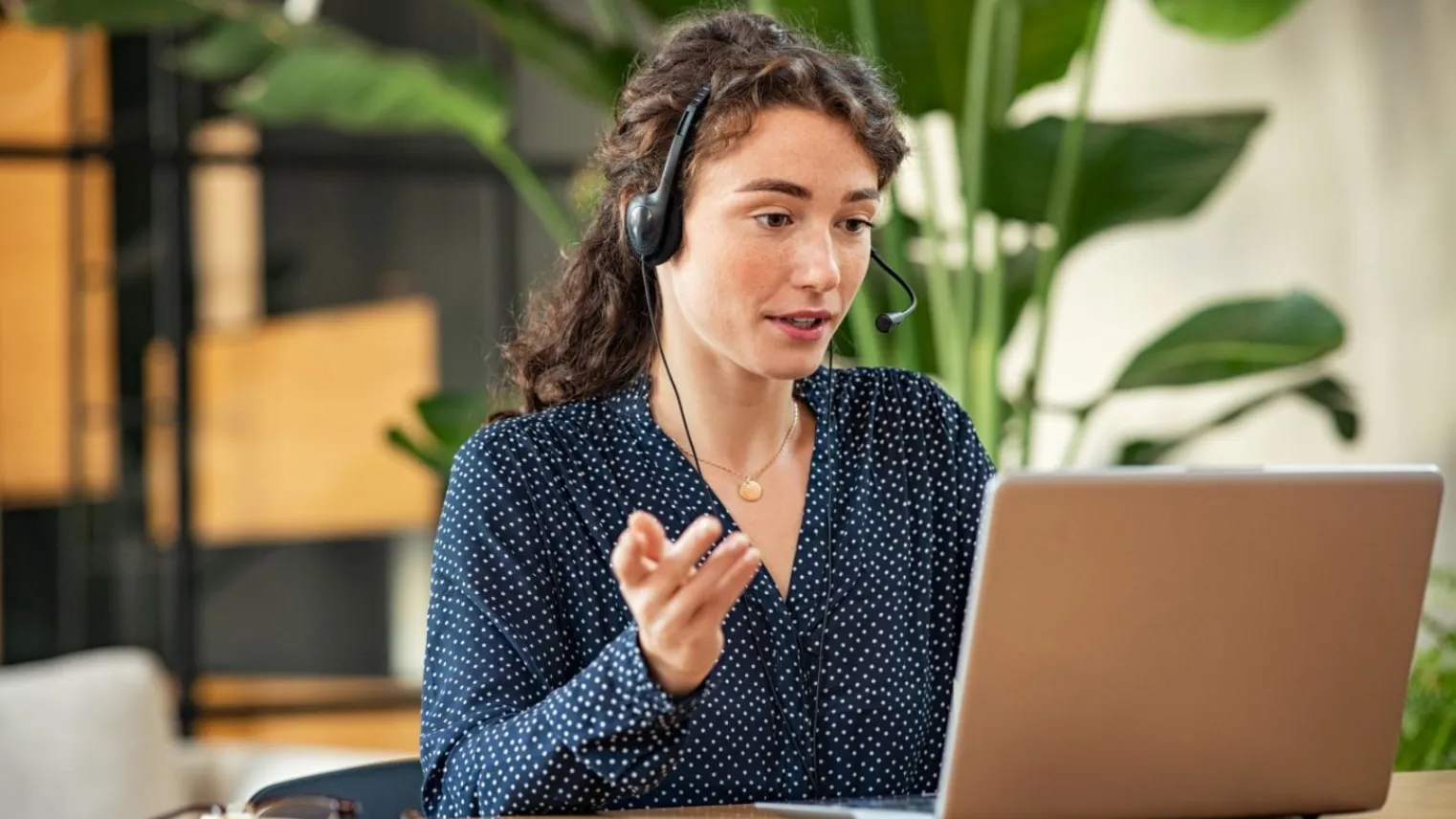 Volwassen vrouw achter de computer met headset als medewerker service desk. 