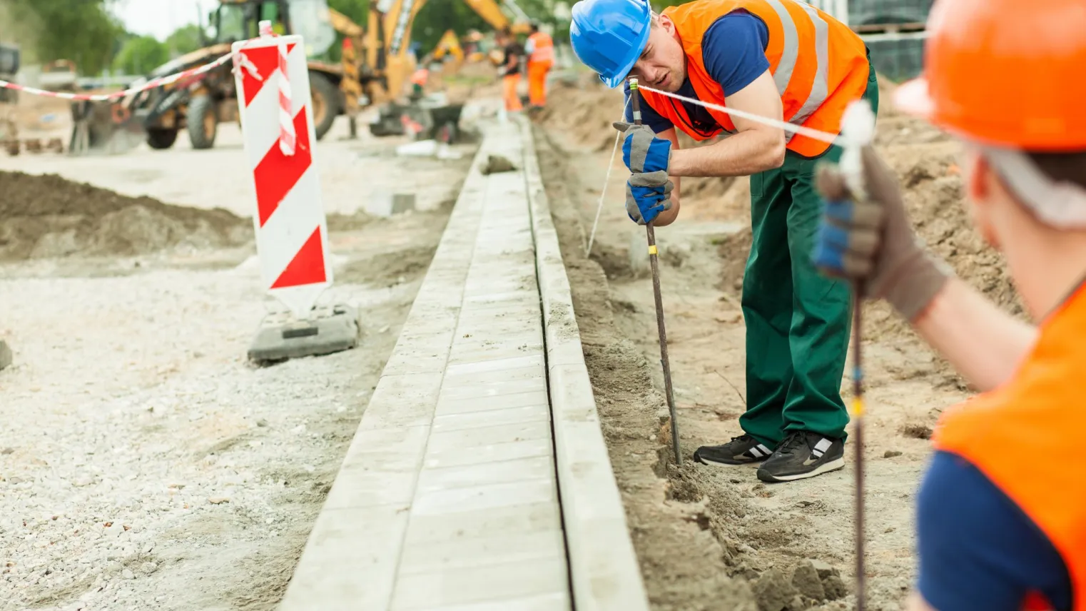 Student Allround Straatmaker controleert of straat recht wordt gelegd met gereedschap 