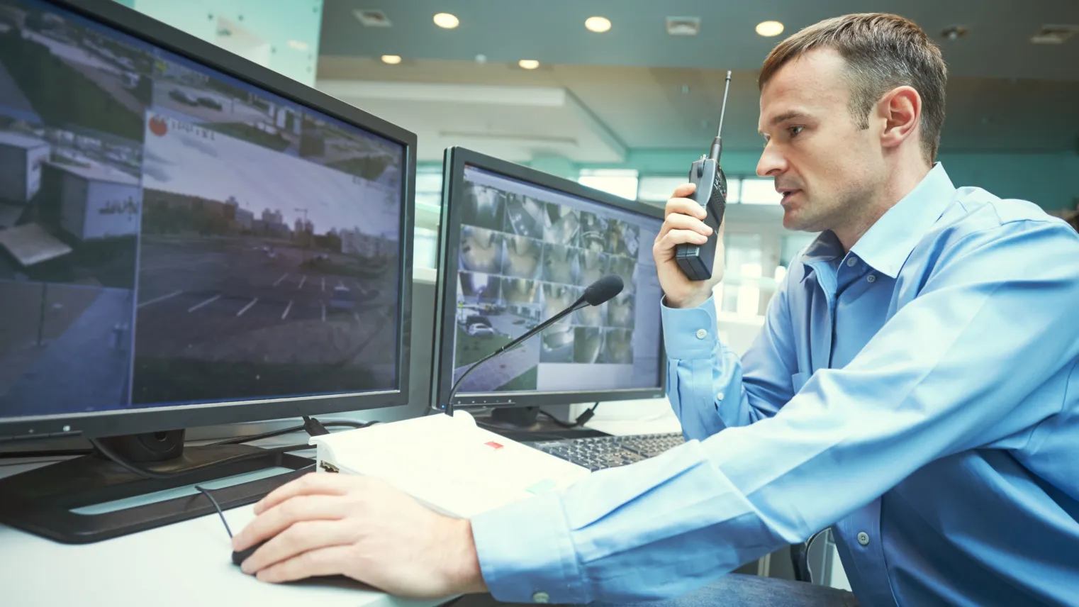 Beveiliger bekijkt beelden van bewakingscamera’s en praat in walkie talkie.