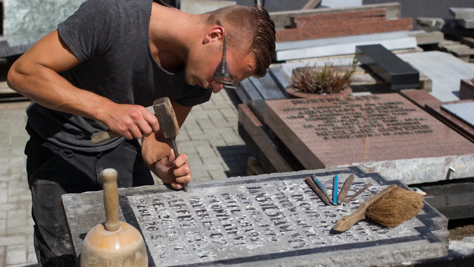 Een student die met focus een stenen monument uithakt.