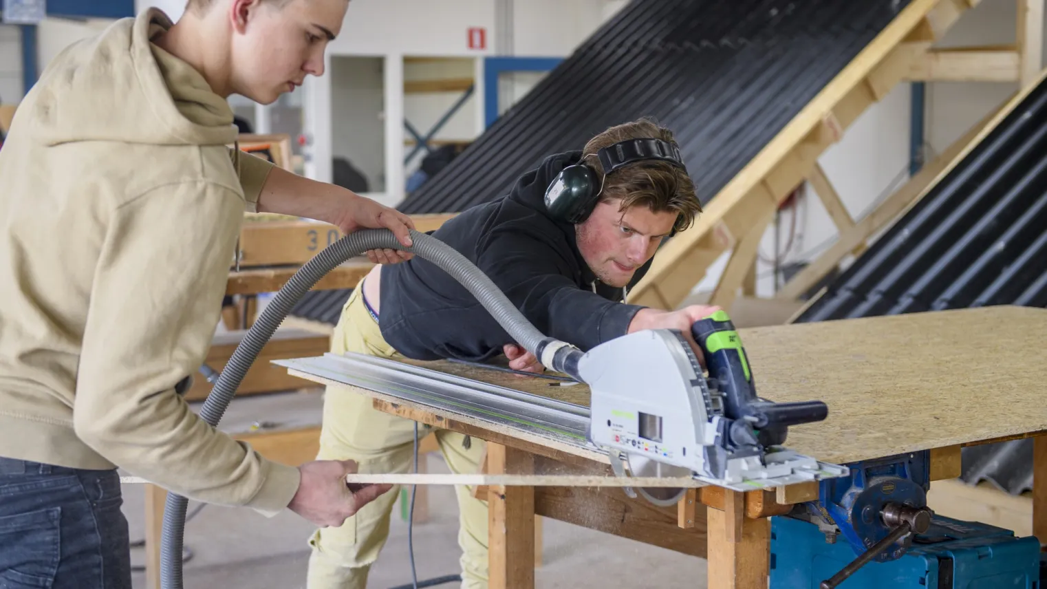 Student van de opleiding Timmerman werkt aan hout project in de werkplaats.