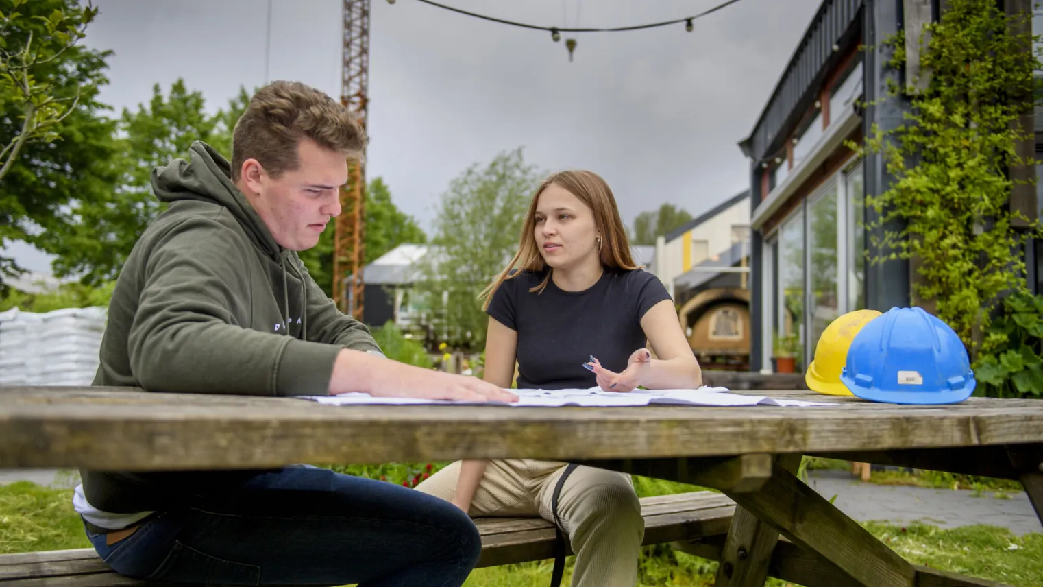 Werkvoorbereider gespecialiseerde aannemerij aan het werk op de bouwplaats met collega.