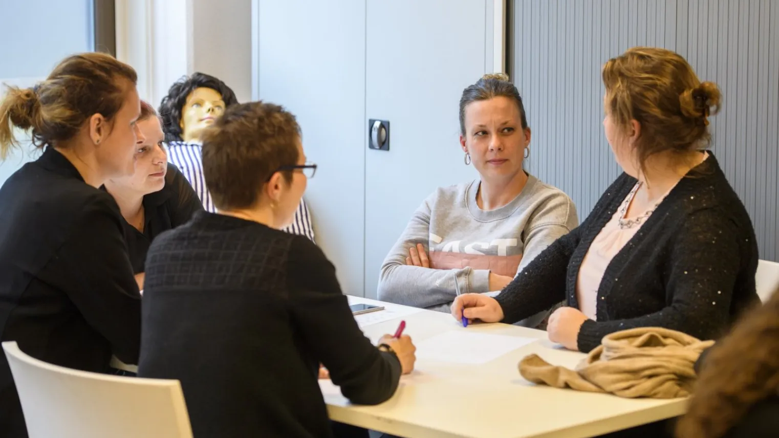 Vijf deelnemers van training BIG herregistratie Klinisch redeneren in gesprek in leslokaal. 