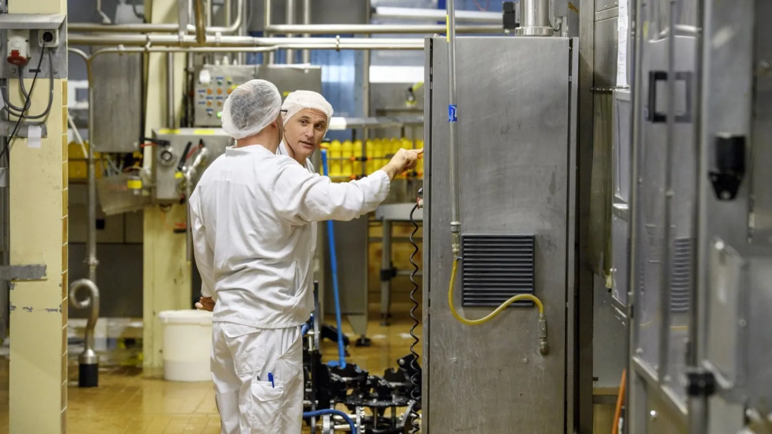 Een student keuzedeel voeding en industriële processen in een machinekamer die op een paneel een controle uitvoert met een praktijkbegeleider. 