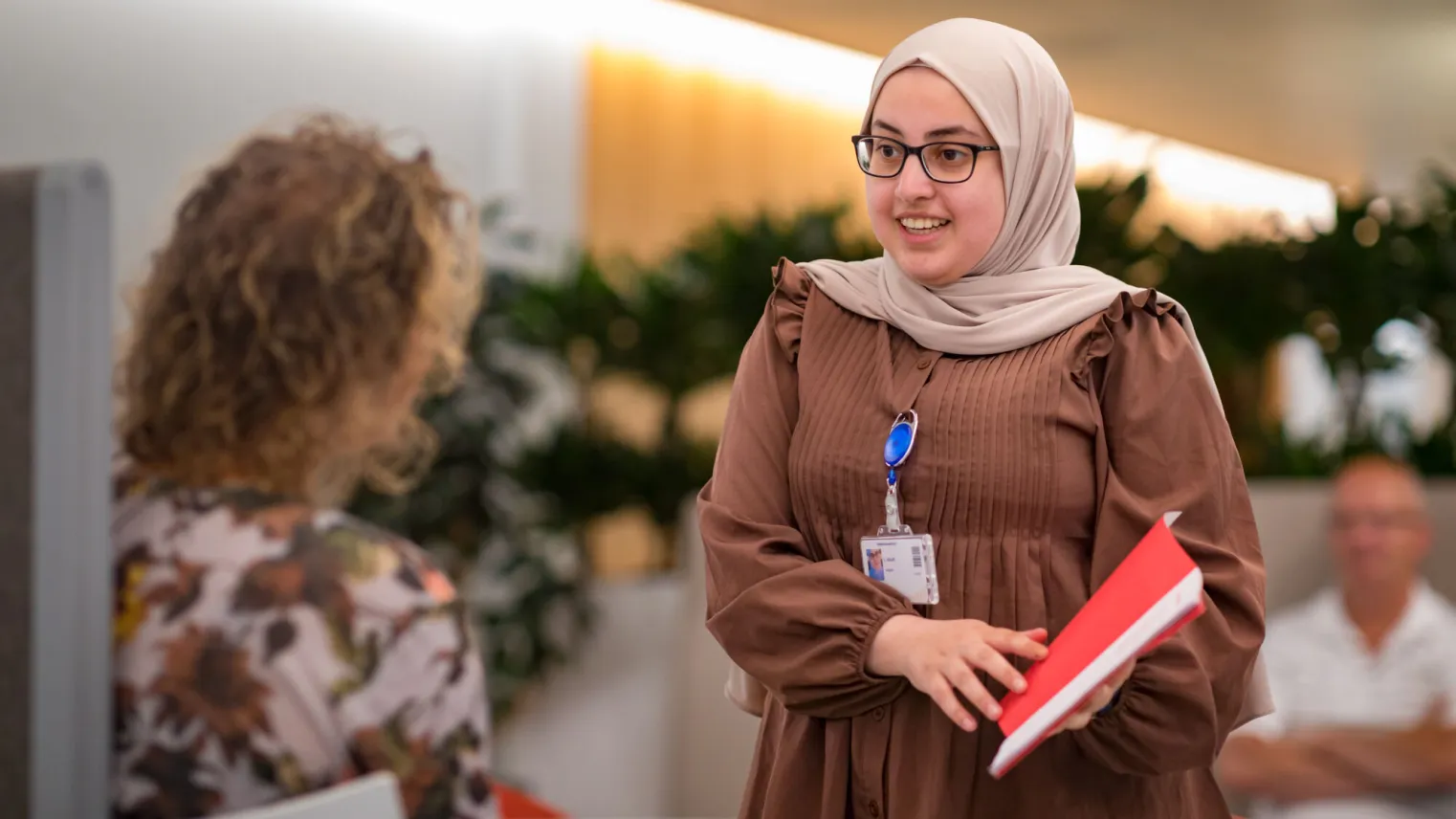 Een vrouw met hijab praat met een andere vrouw.