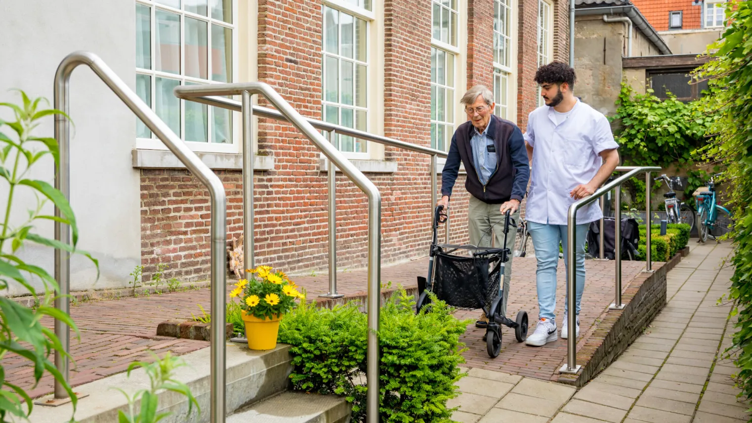 Twee mannen wandelen buiten met een looprek.