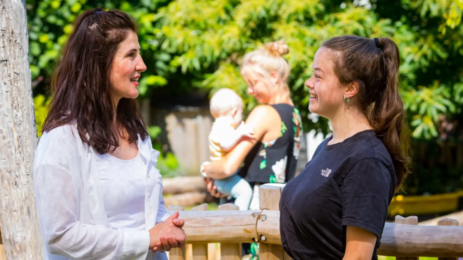 Twee pedagogisch medewerkers in gesprek buiten bij kinderdagverblijf 