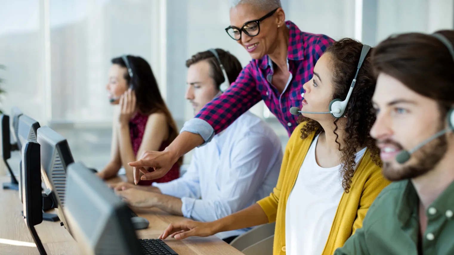 Leidinggevende geeft instructies aan medewerkers van callcenter.