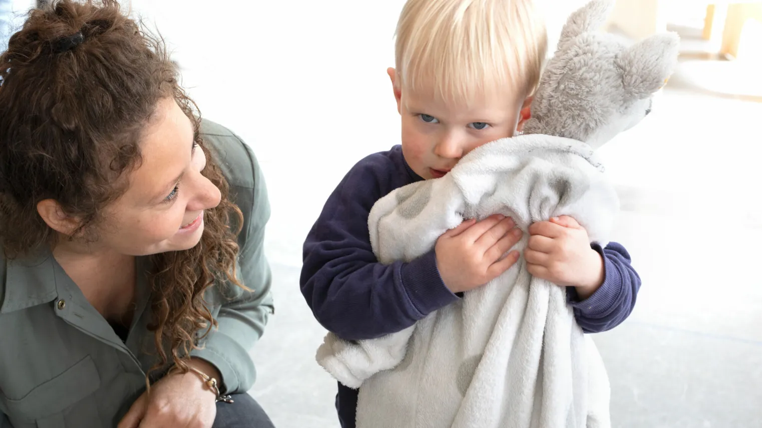 Pedagogisch medewerker is met een klein kind bezig op de dagopvang