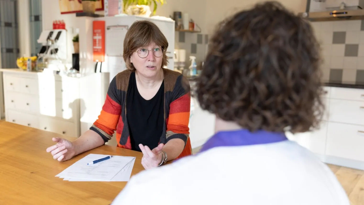 Praktijkopleider in gesprek over kwaliteitsborging met collega aan tafel. 