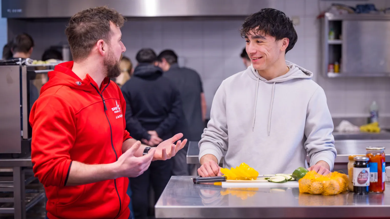 Twee mannen praten met elkaar in een keuken.