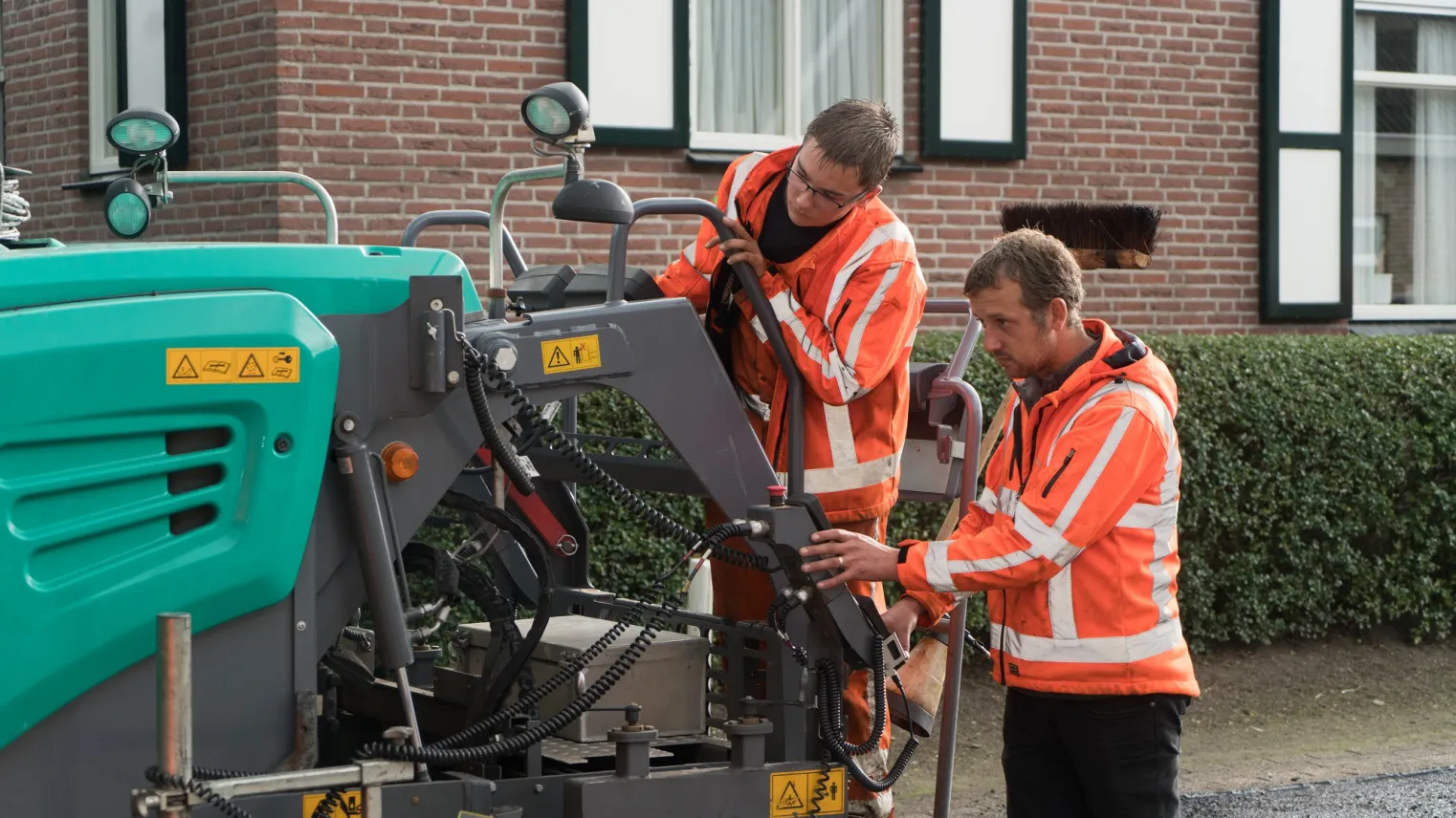 Studenten Balkman werken samen op een machine aan de weg 