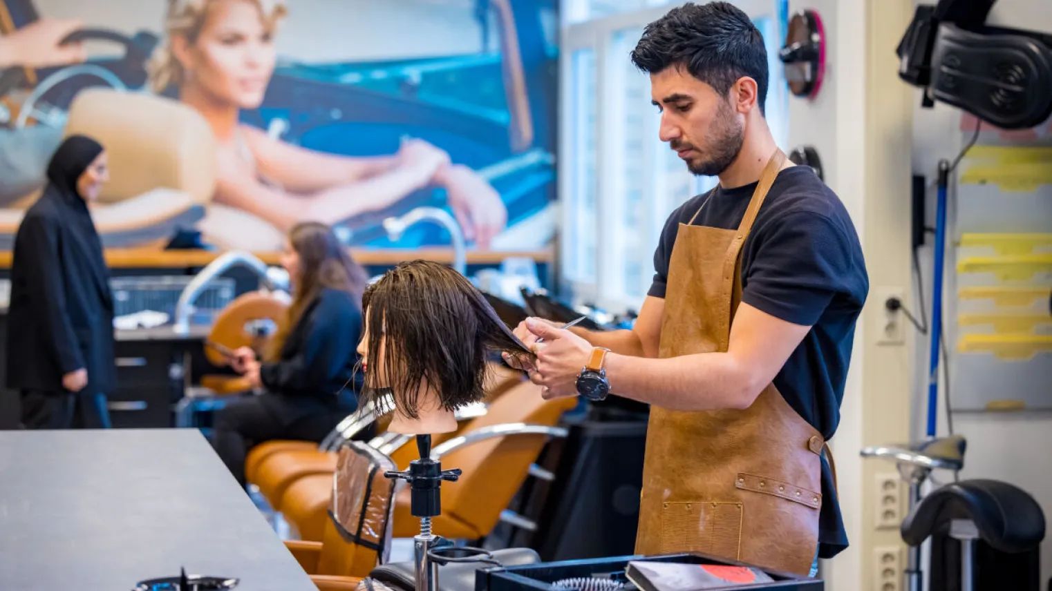 Student oefent met knippen in schoolsalon