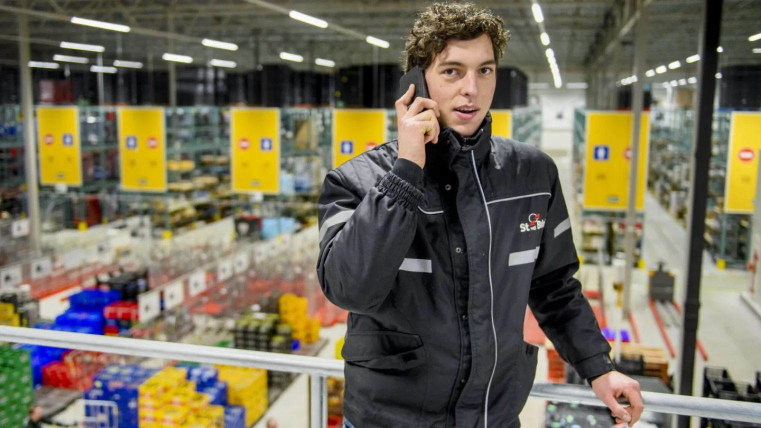 Student logistiek teamleider aan het bellen in een groot magazijn