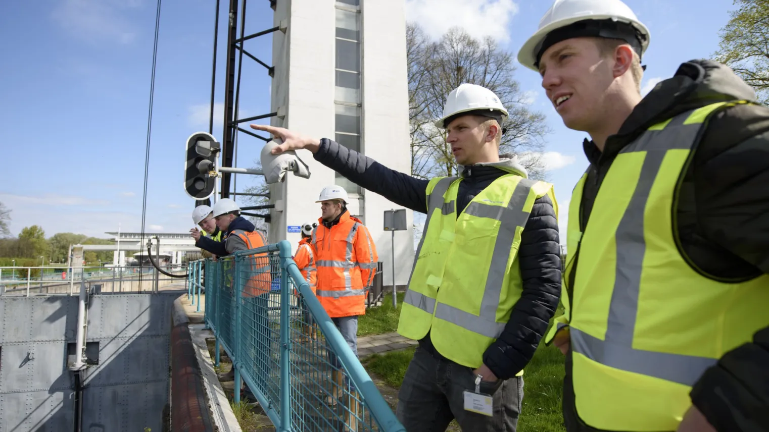 Studenten werken samen op een brug en dragen hesjes voor de veiligheid 