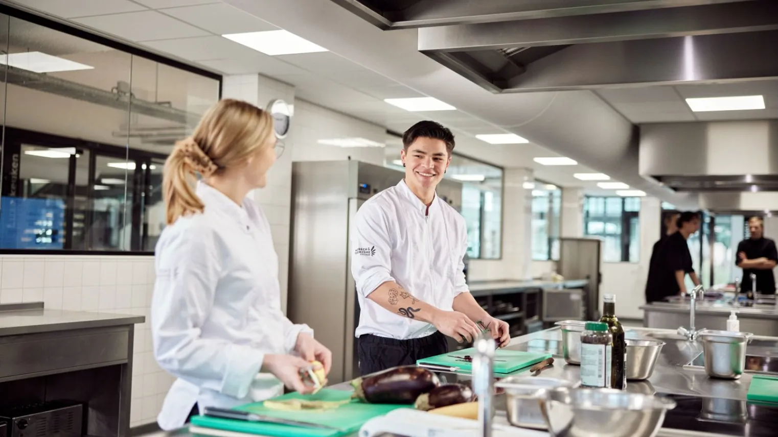 Studenten Zelfstandig Werkend Kok snijden groente in moderne keuken op school 