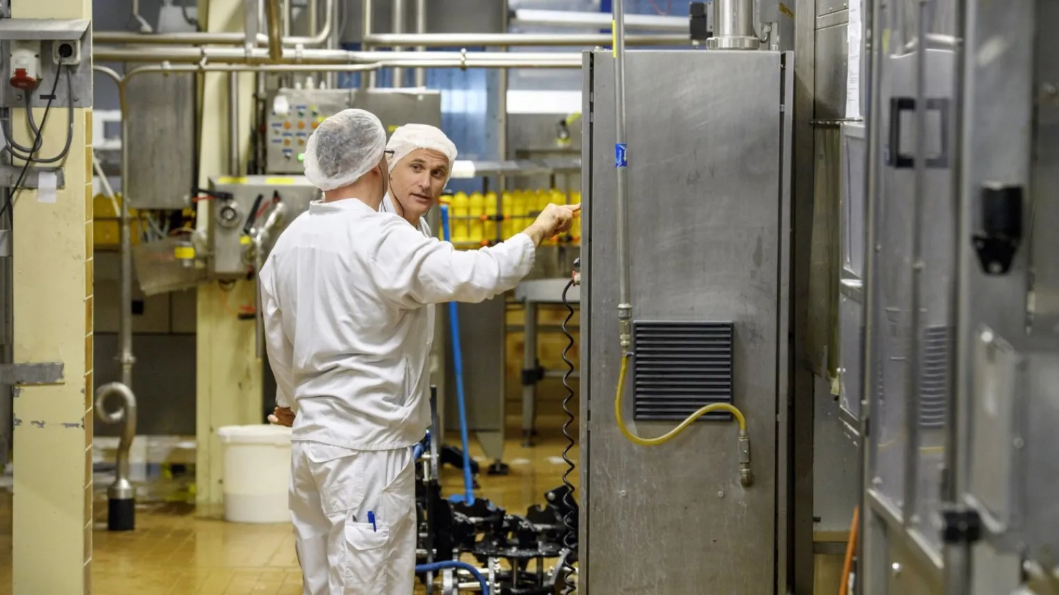 Een student in een machinekamer die op een paneel een controle uitvoert met een praktijkbegeleider. 