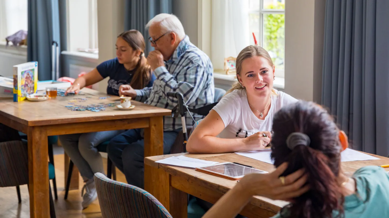 Mensen zitten aan tafel in eetkamer. 