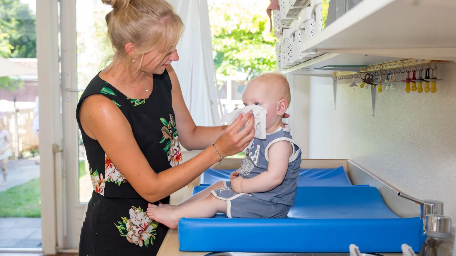 pegagogisch medewerker met certificaat aan het werk met een baby.