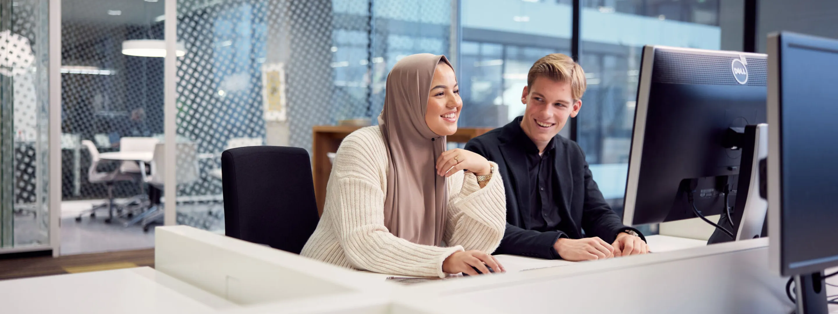 Twee leerlingen achter een computer in een werkruimte