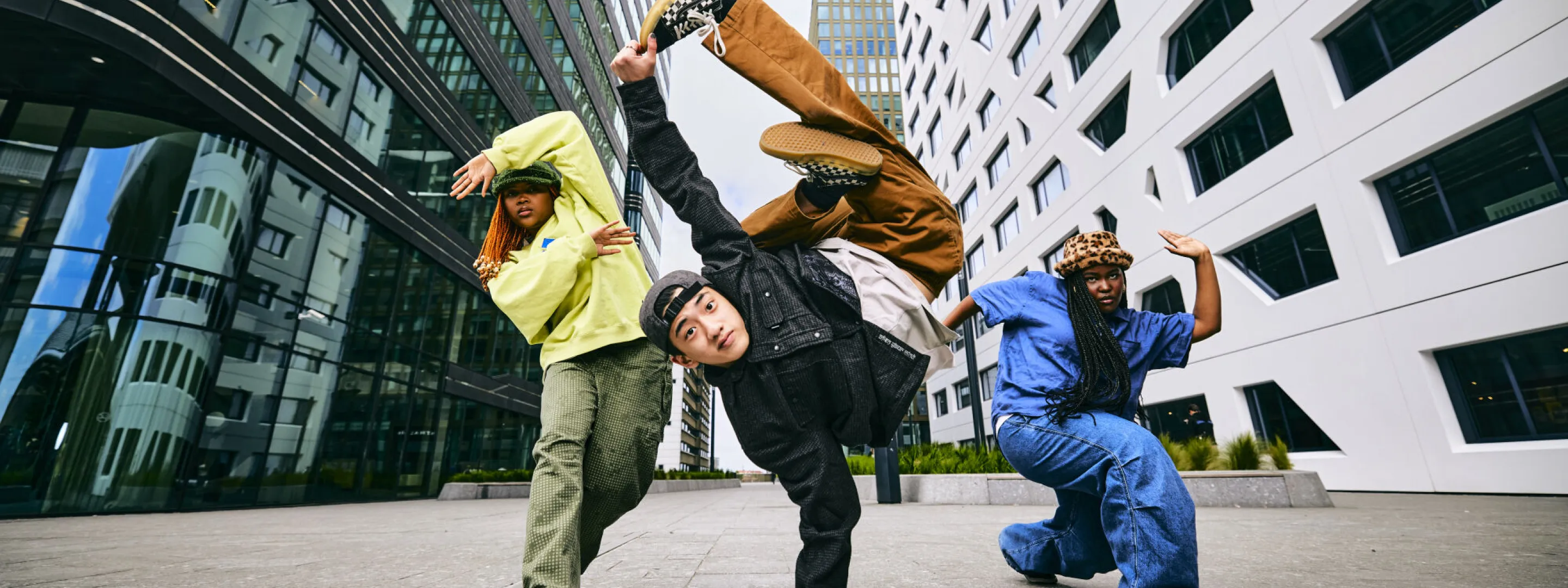 Drie dansers nemen een pose aan, tussen gebouwen bij het gemeentehuis van Utrecht