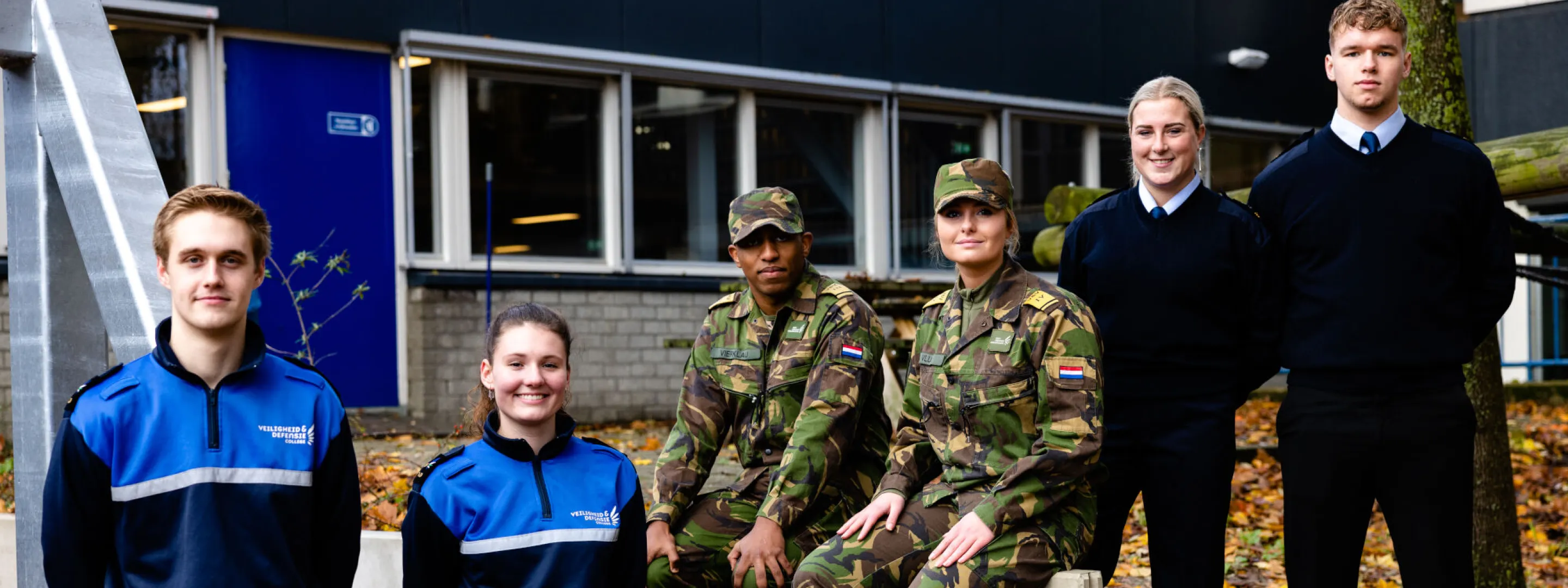 Zes leerlingen veiligheid staan in hun tenue voor het college gebouw. 