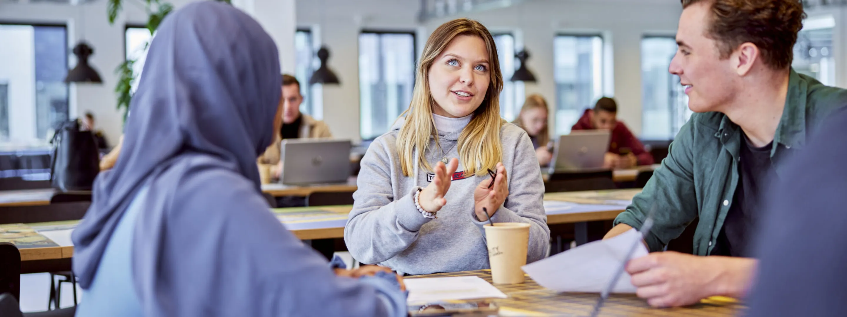 studenten zitten aan tafel en praten met elkaar