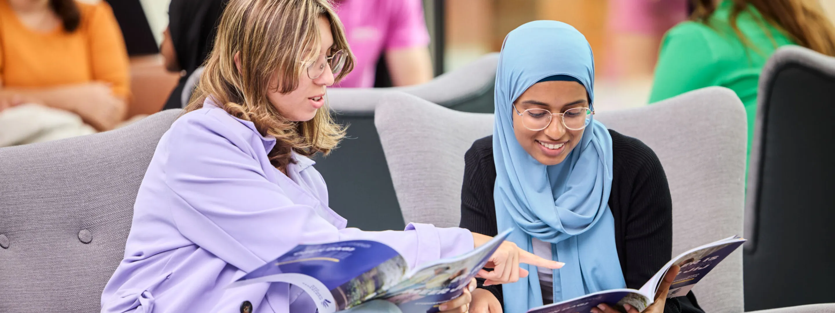 twee studiekiezers bladeren in een studiekeuzegids om te kijken welke mogelijkheden er zijn